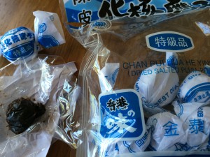 A package of wrapped dried salted pitted plums and an unwrapped one (similar to Chinese medicine balls).